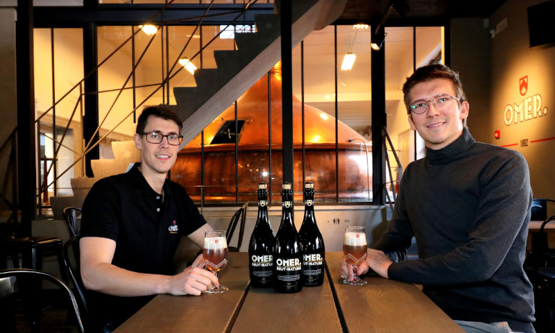 Omer Gerry en nog een man aan tafel met flessen en glazen OMER Brut Nature in de brouwerij